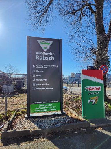 Informationstafel mit Dienstleistungen und Standortangaben. Im Hintergrund Bäume und Gebäude.